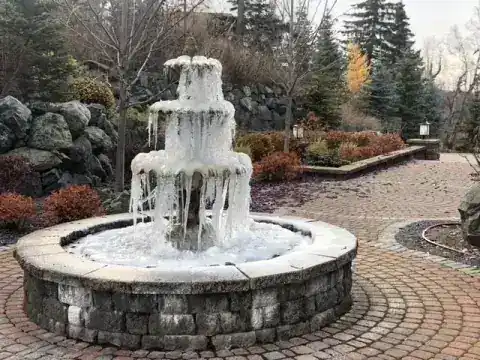 Tiered stone fountain in a circular basin on a brick paver courtyard