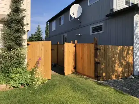 Cedar privacy fence and double gate running along the side of a house