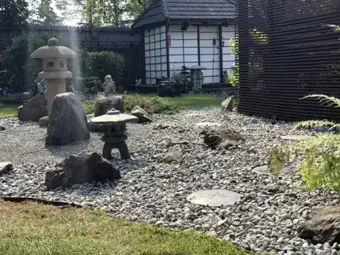 Zen rock garden of gravel, boulders and stone lanterns beside a tea house