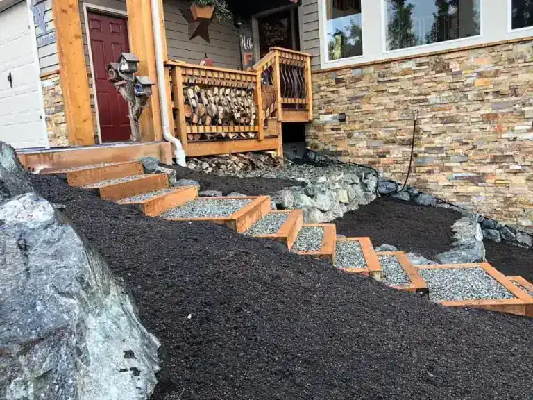 Timber-framed gravel steps climbing to a front entrance with stone veneer